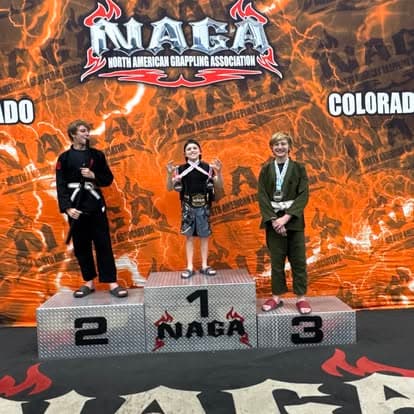 Imperial students standing on the first, second and third place podium at a NAGA grappling tournament