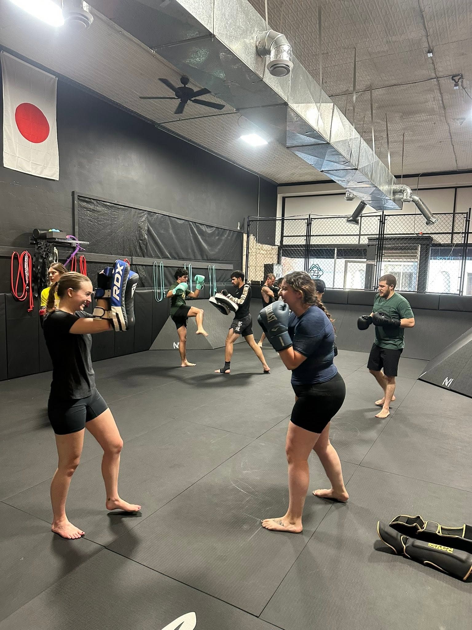 Two students sparring with boxing gloves on the mat during a Muay Thai class